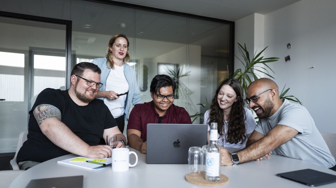 Projekt-Squad der Shopware Agentur mindshape sitzt in Konferenzraum und schaut auf Laptop